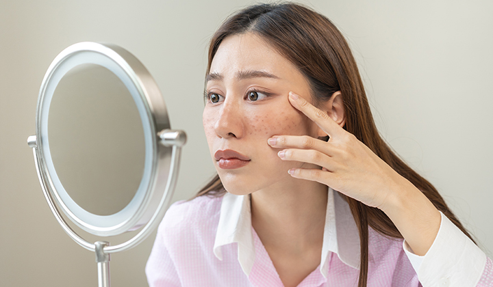 画像：鏡で目元をチェックする女性